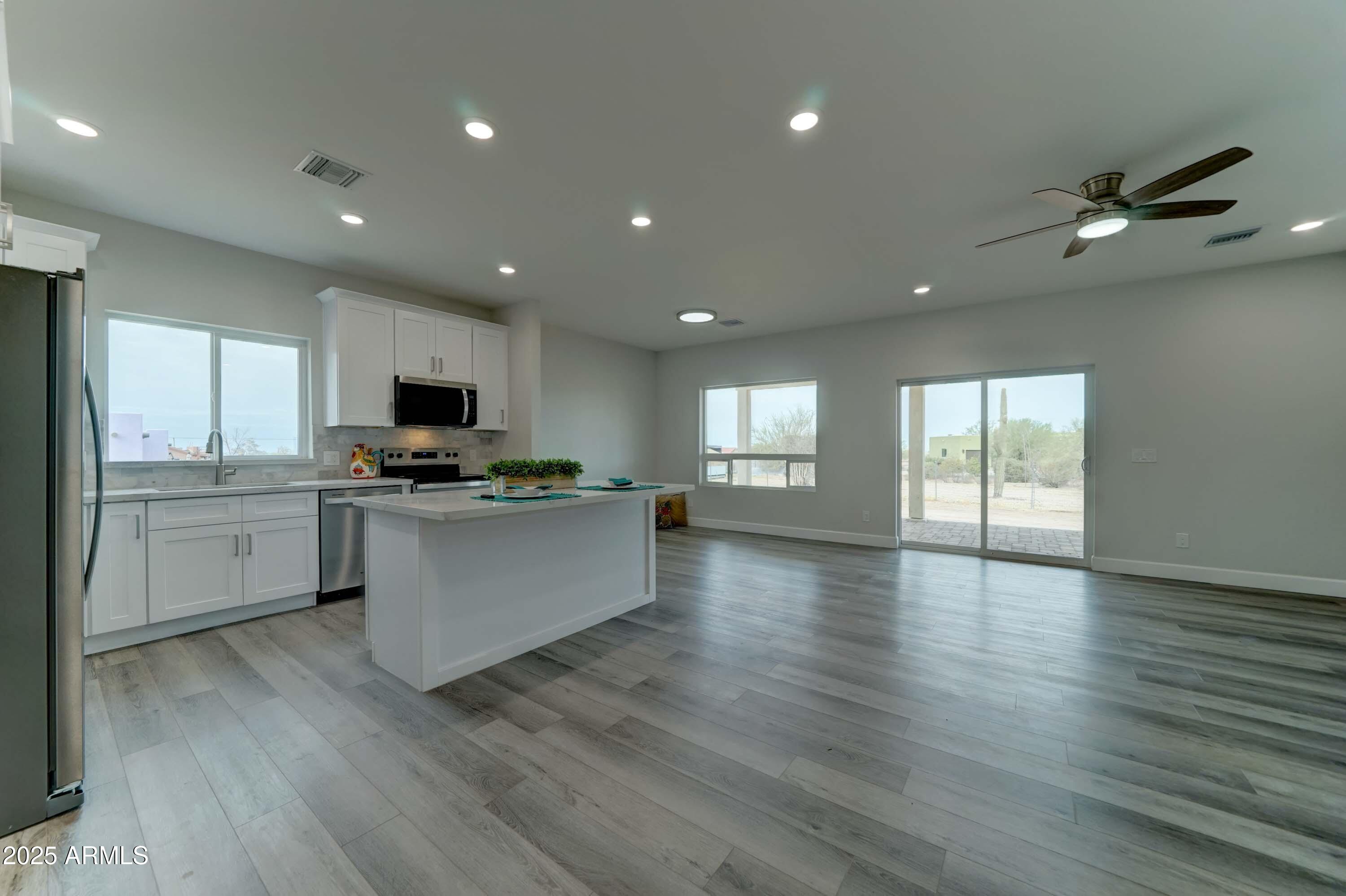 4294 North Wolverine Pass Road Apache Junction, AZ 85119 - Photo 6 of 37 a open kitchen with white cabinets a sink dishwasher and a stove with wooden floor