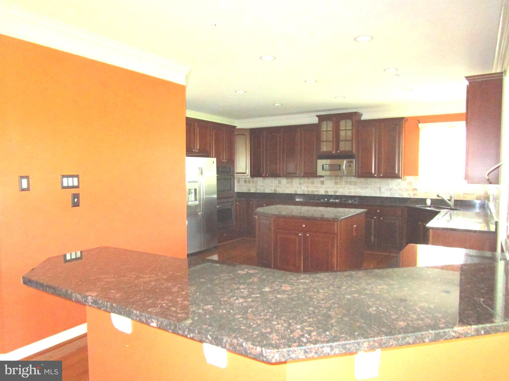 14204 Derby Ridge Road Bowie, MD 20721 - Photo 3 of 27 a large kitchen with kitchen island granite countertop a stove a sink and a granite counter space