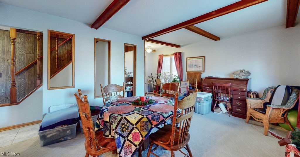 Dining space featuring beamed ceiling and light colored carpet