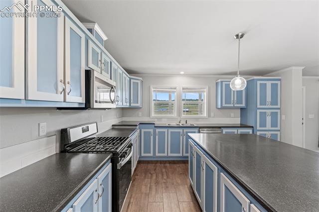 567 High Pasture Road Florissant, CO 80816 - Photo 14 of 48 Kitchen with stainless steel appliances, solid surface countertops, blue cabinetry, crown molding, and loads of cabinets, huge island