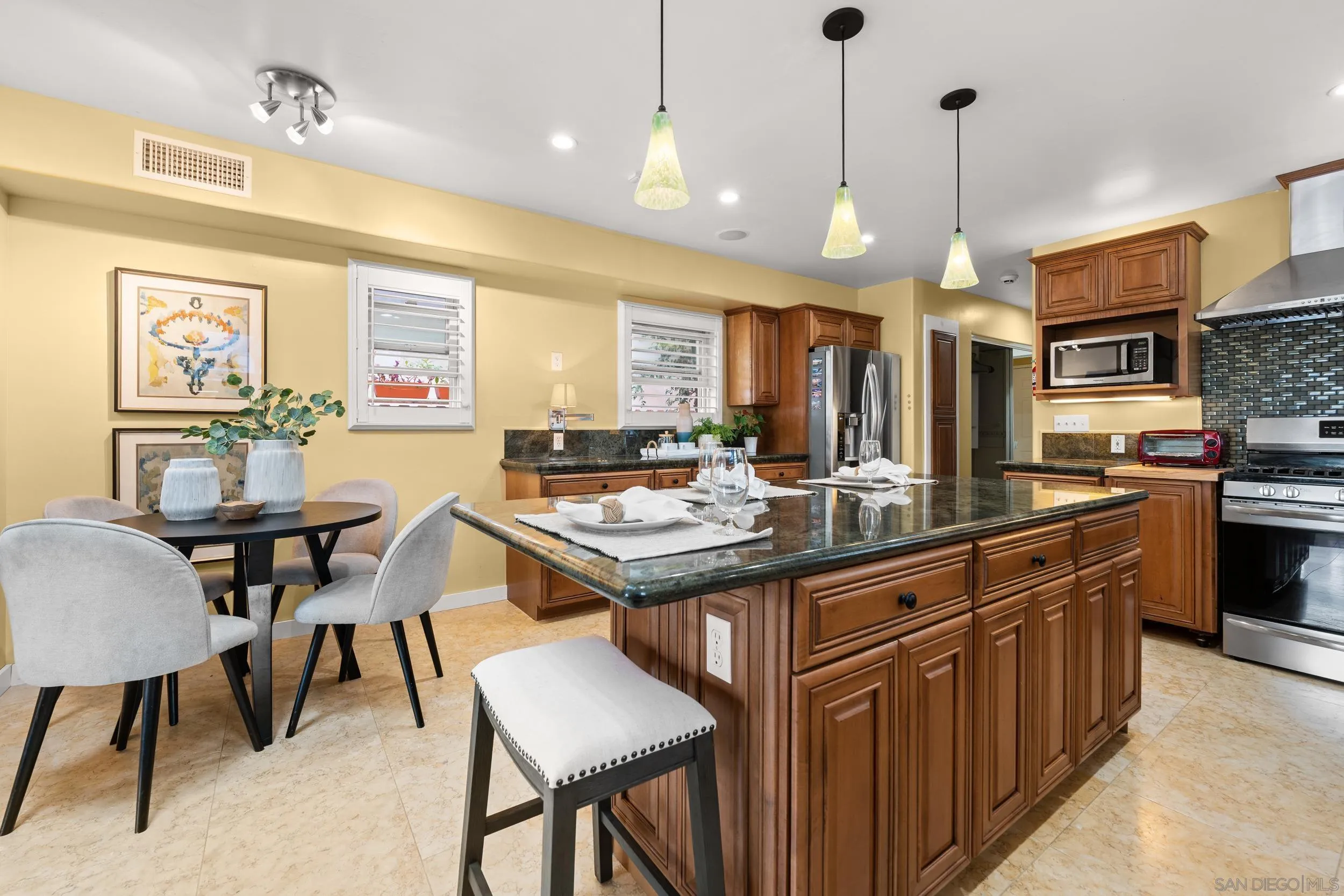 4685 Long Branch Avenue San Diego, CA 92107 - Photo 6 of 27 a kitchen with stainless steel appliances granite countertop a stove a sink dishwasher a dining table and chairs with wooden floor