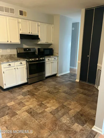 a kitchen with granite countertop a stove a sink and a refrigerator