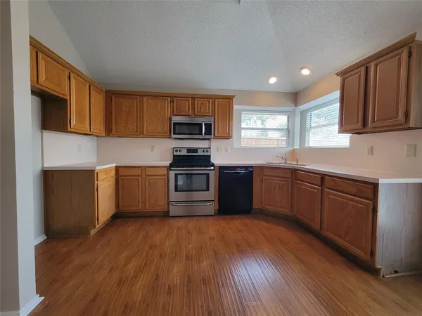 a kitchen with a sink wooden floor and stainless steel appliances