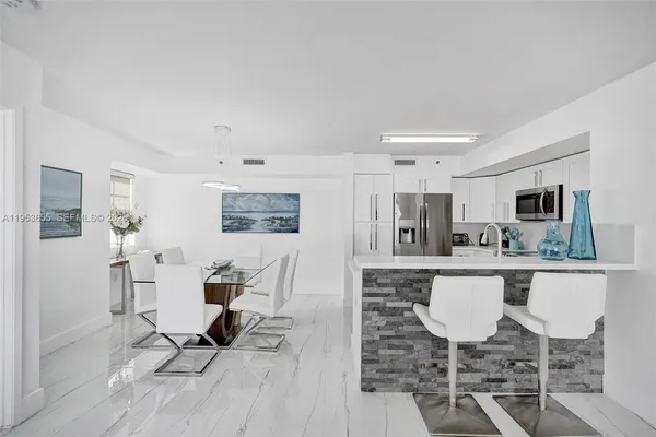 a living room with stainless steel appliances a dining table wooden floor and kitchen view