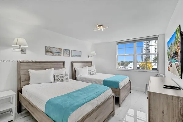 a bedroom with 2 bed and a large window