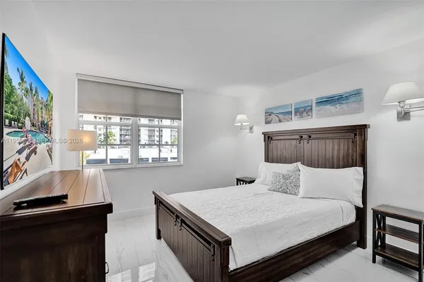 a bedroom with a bed and a flat tv screen on the dresser