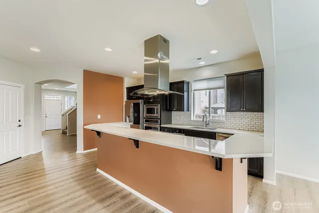 a kitchen with stainless steel appliances a sink and wooden floor