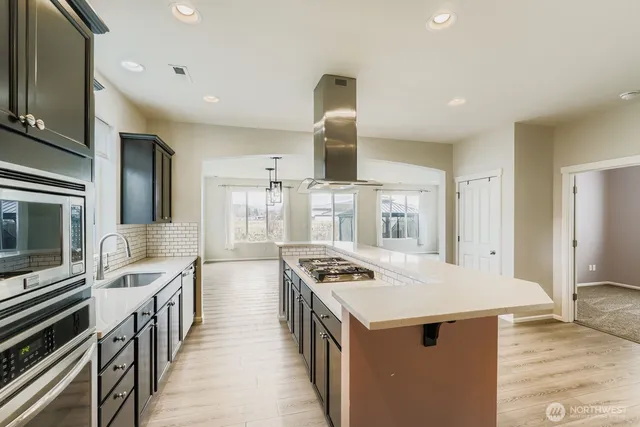 a kitchen with stainless steel appliances a stove top oven a sink dishwasher a refrigerator and a stove