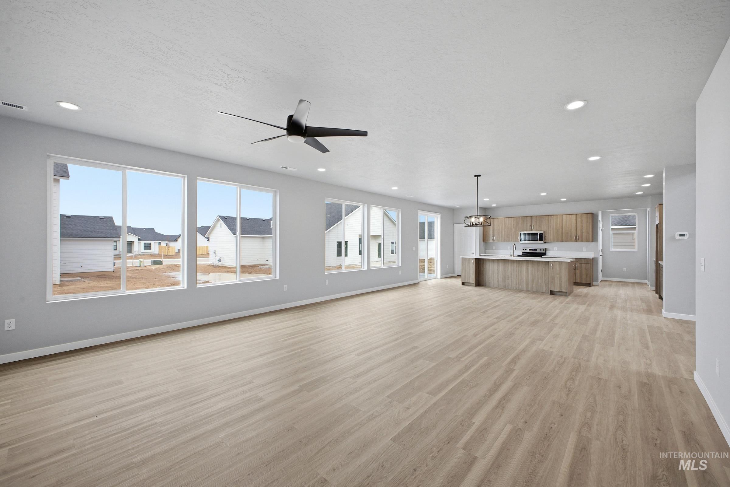 13672 Redway Court Caldwell, ID 83607 - Photo 10 of 34 Unfurnished living room featuring a ceiling fan, light wood-type flooring, and a chandelier