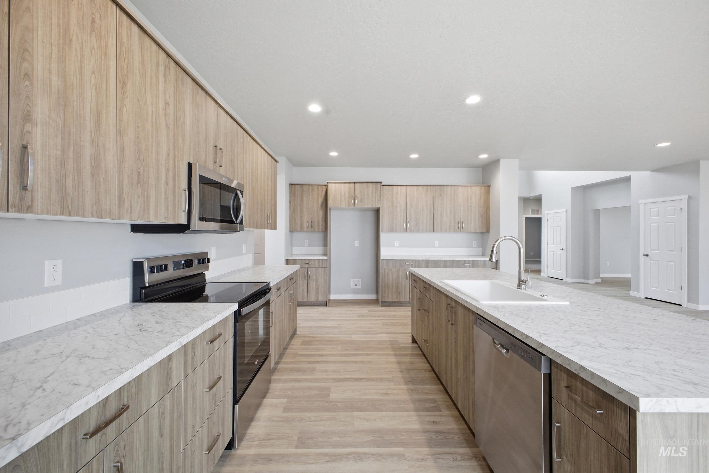 13672 Redway Court Caldwell, ID 83607 - Photo 5 of 34 Kitchen featuring stainless steel appliances, a large island with sink, light wood finish cabinetry, and recessed lighting