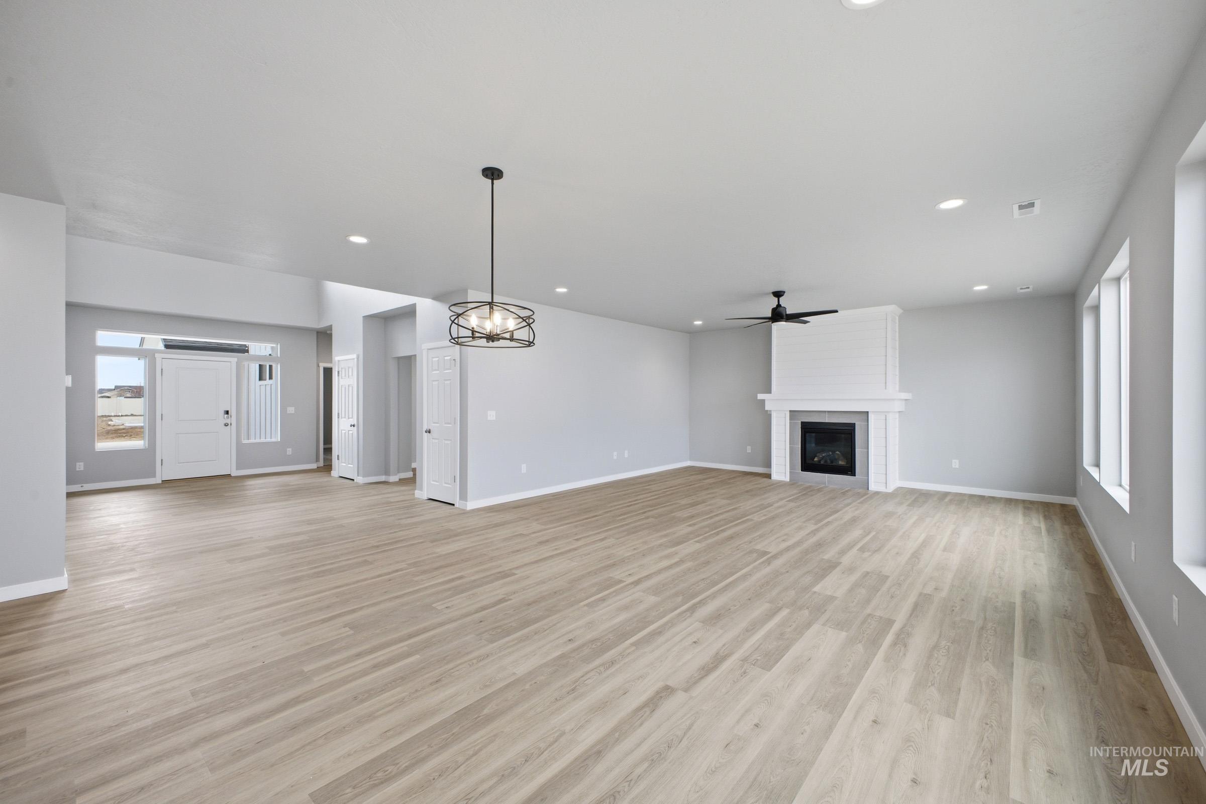13672 Redway Court Caldwell, ID 83607 - Photo 9 of 34 Unfurnished living room with a large fireplace, suspended lighting, ceiling fan, and light wood finished floors