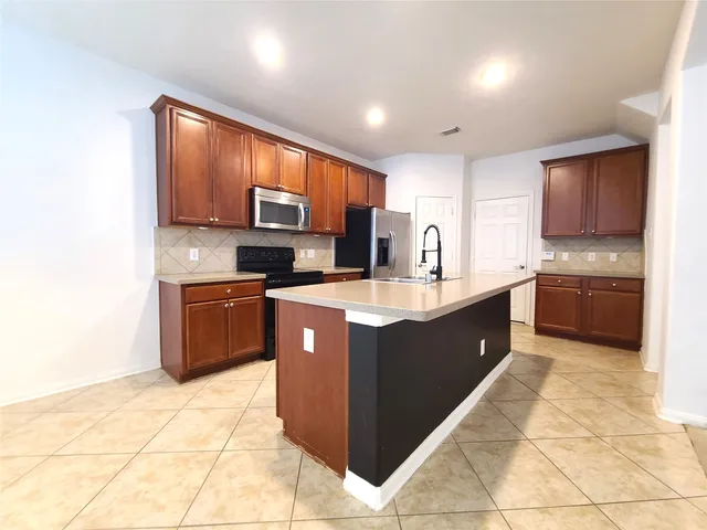 a large kitchen with stainless steel appliances granite countertop a stove a sink dishwasher a microwave oven and a refrigerator