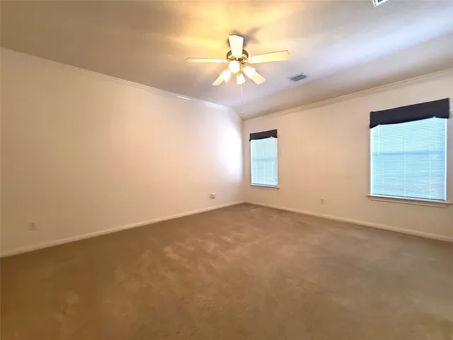 an empty room with a chandelier fan and windows