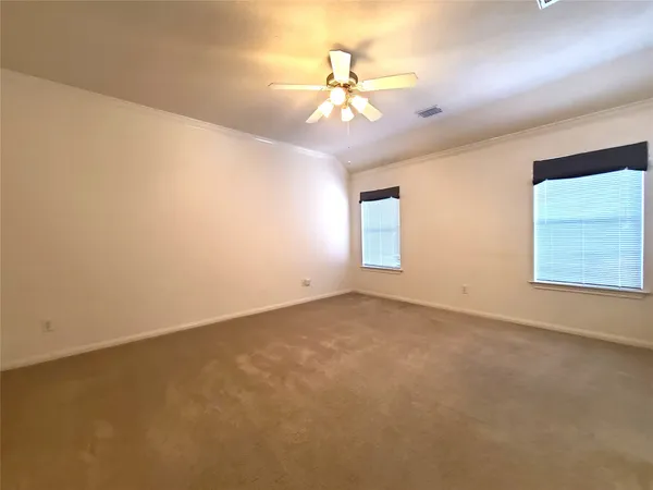 an empty room with a chandelier fan and windows