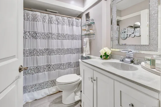 a bathroom with a granite countertop sink a toilet and a shower