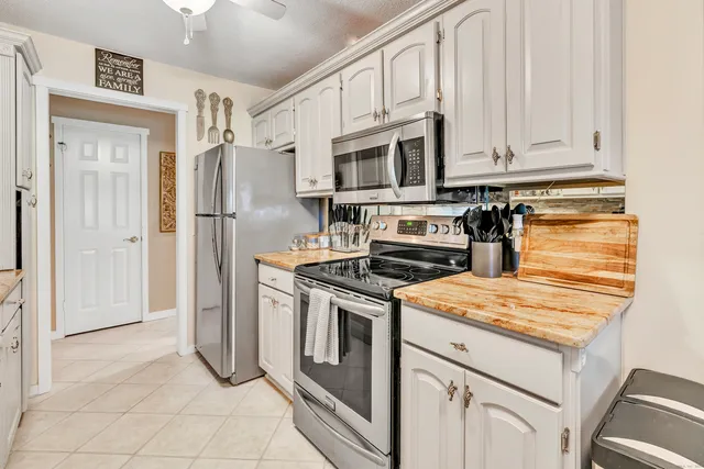 a kitchen with stainless steel appliances granite countertop a refrigerator stove and white cabinets