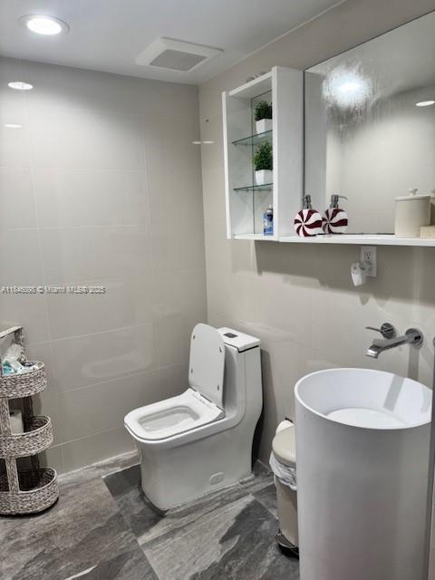 4229 West 7th Lane Hialeah, FL 33012 - Photo 4 of 6 a bathroom with a toilet a sink and mirror
