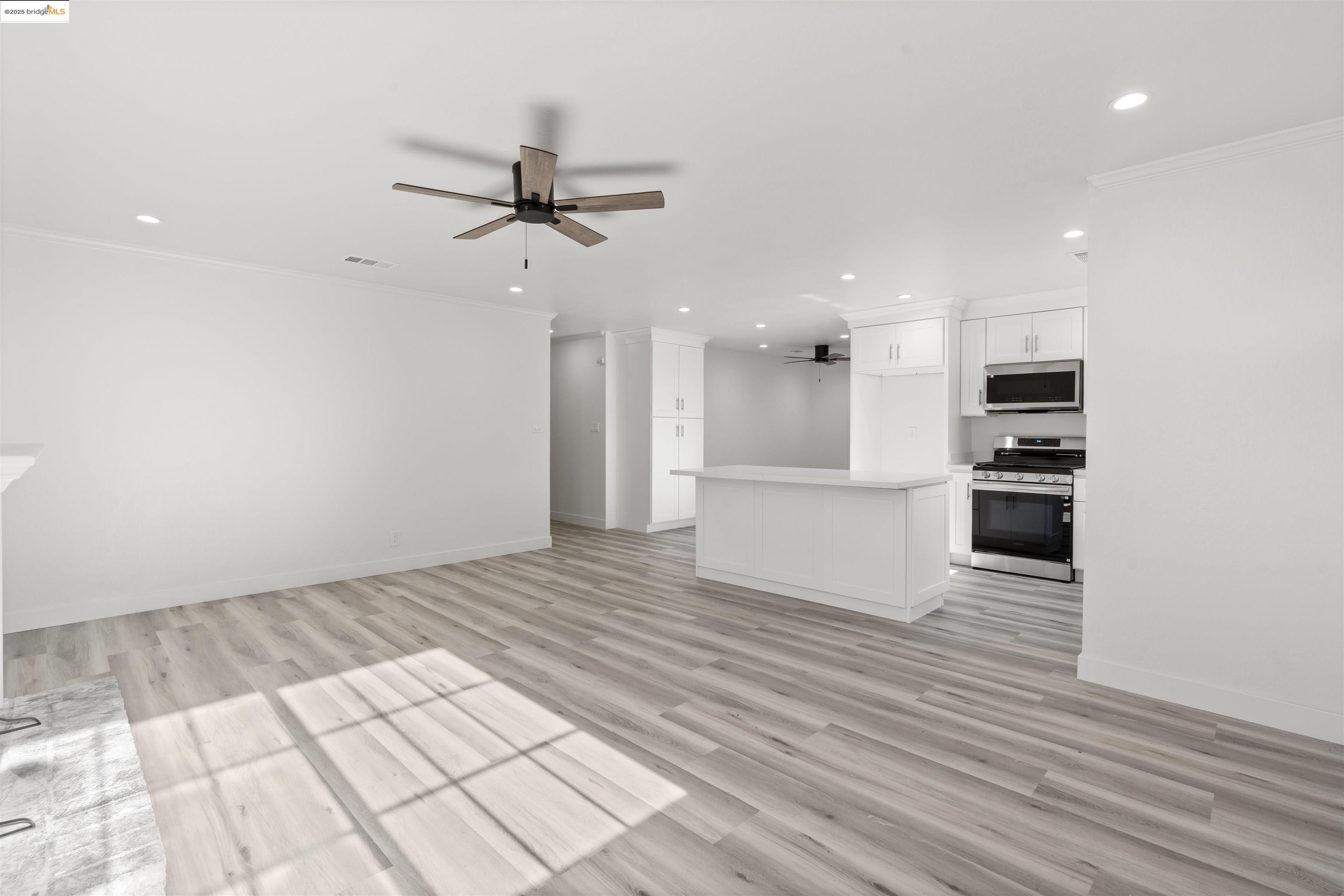 an empty room with wooden floor kitchen view and a window