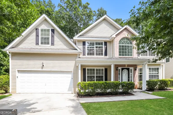 a front view of a house with a yard and potted plants