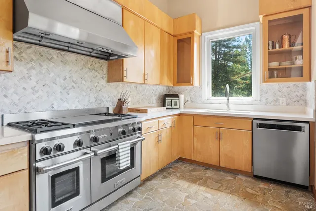 a kitchen with stainless steel appliances a stove a sink and white cabinets