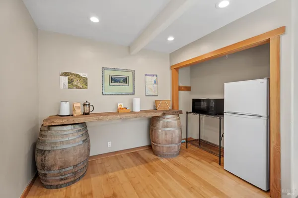 a living room with stainless steel appliances furniture a refrigerator and a wooden floor