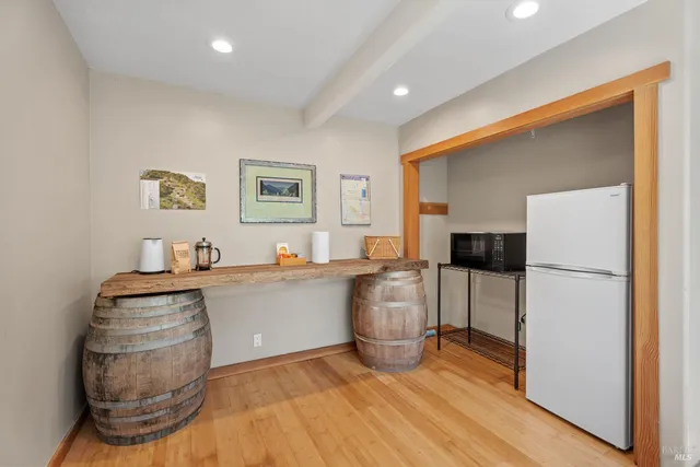 a living room with stainless steel appliances furniture a refrigerator and a wooden floor