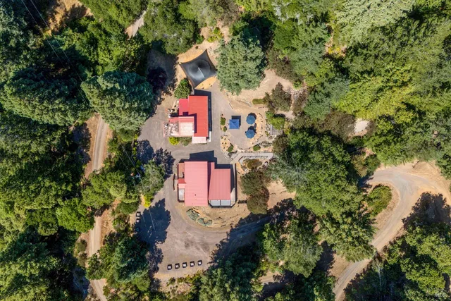 an aerial view of residential house with outdoor space and trees all around