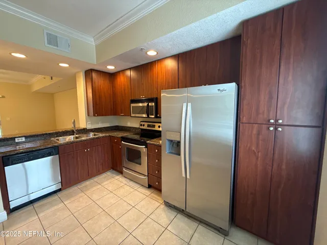 a large kitchen with stainless steel appliances granite countertop a refrigerator and a sink