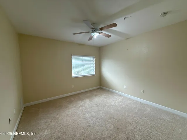 an empty room with a window and a fan