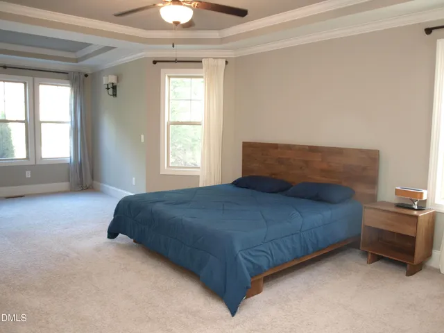a bedroom with a bed next to a window and a chandelier