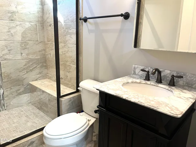 a bathroom with a granite countertop sink toilet and shower