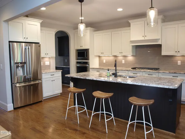 a kitchen with stainless steel appliances granite countertop a table chairs stove microwave and refrigerator