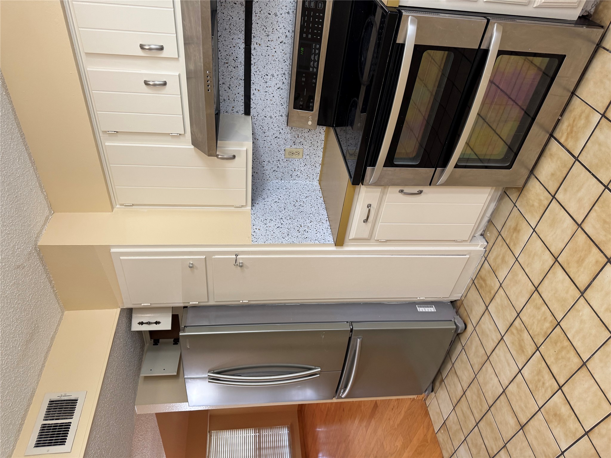 1748 Timberwood Drive Austin, TX 78741 - Photo 20 of 22 Kitchen with stainless steel range, refrigerator, white cabinets, a textured ceiling, and exhaust hood