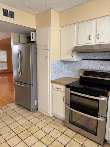 a kitchen with granite countertop a refrigerator and a stove top oven