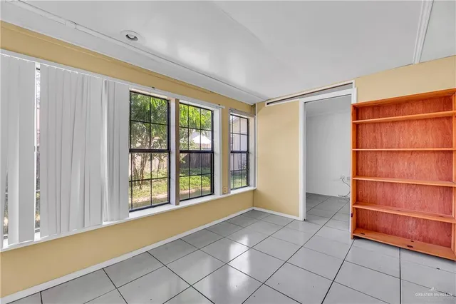a view of an empty room with bathroom and a window