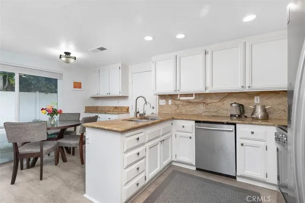a kitchen with granite countertop cabinets sink and white stainless steel appliances