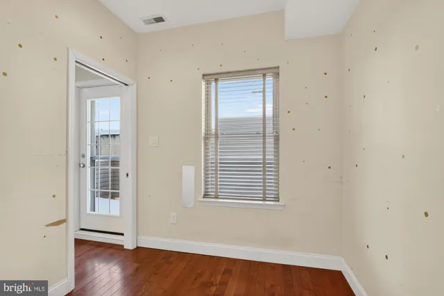 an empty room with wooden floor and windows