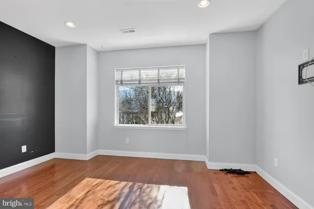 an empty room with wooden floor and windows