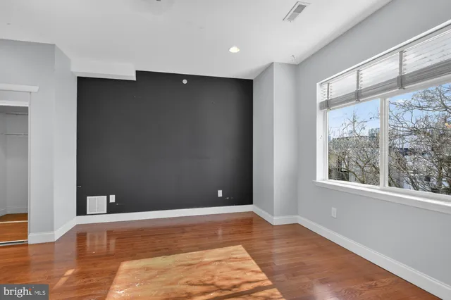 a view of an empty room with window and wooden floor