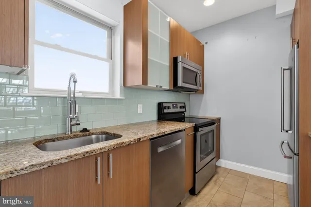 a kitchen with stainless steel appliances granite countertop a sink a stove and a microwave