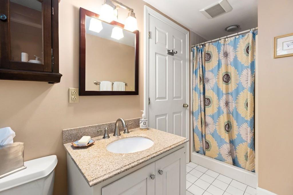 228 Cochituate Road Wayland, MA 01778 - Photo 22 of 32 a bathroom with a granite countertop sink a toilet and a shower curtain
