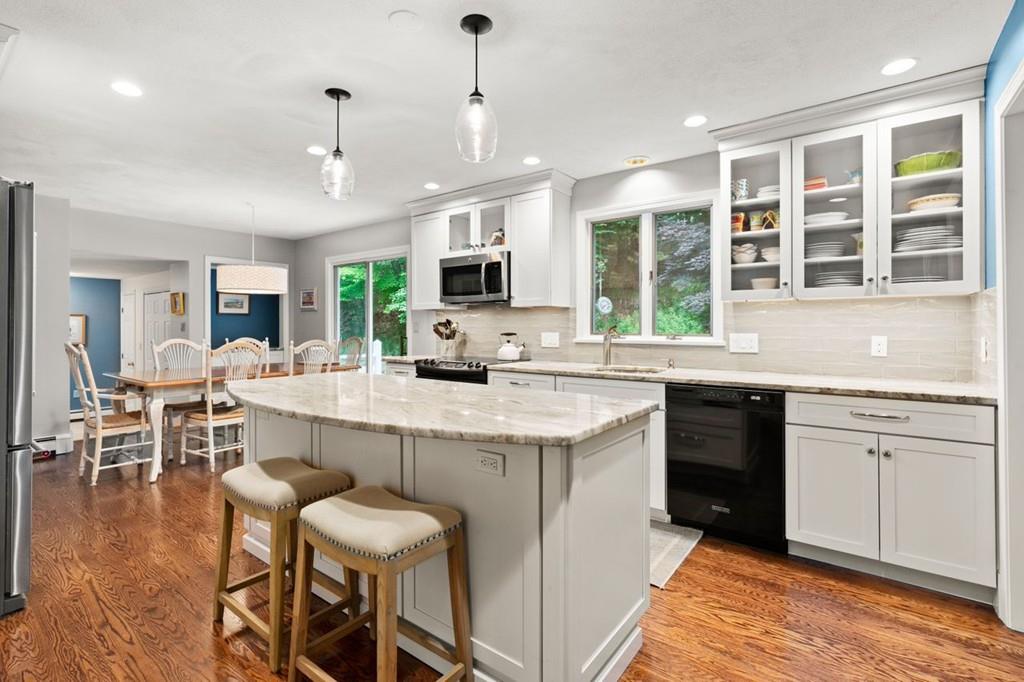 228 Cochituate Road Wayland, MA 01778 - Photo 4 of 32 a kitchen with stainless steel appliances granite countertop a stove top oven a sink dishwasher a dining table and chairs with wooden floor
