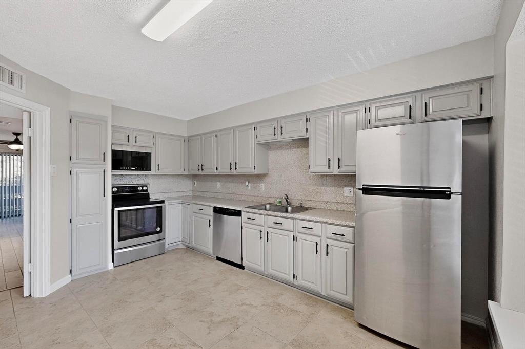 5840 Spring Valley Road, Unit 810 Dallas, TX 75254 - Photo 15 of 40 a kitchen with stainless steel appliances a refrigerator sink and white cabinets