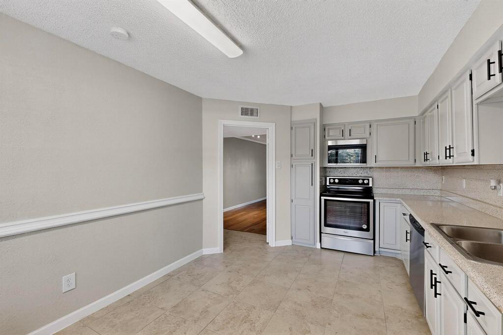 5840 Spring Valley Road, Unit 810 Dallas, TX 75254 - Photo 16 of 40 a kitchen with stainless steel appliances a stove microwave and cabinets