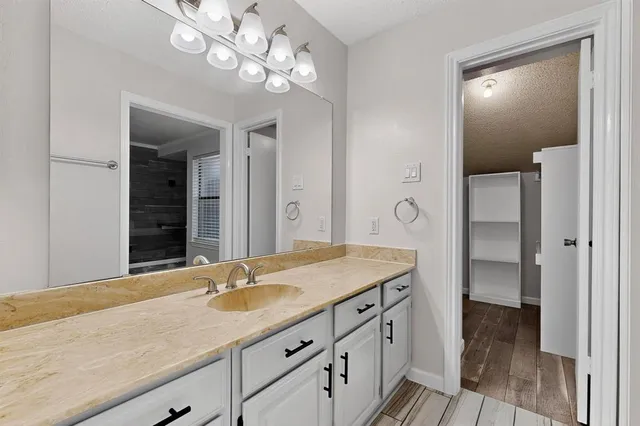 a bathroom with a granite countertop sink a light fixture and a mirror