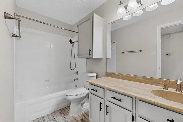 a bathroom with a granite countertop sink a toilet a mirror and shower