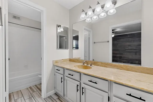 a bathroom with a granite countertop sink a large mirror and a bathtub