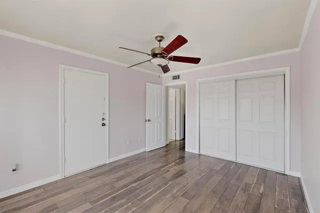 a view of a room with wooden floor and a ceiling fan