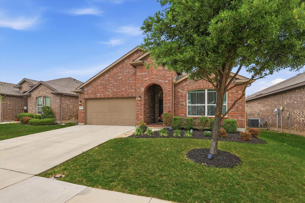 11500 Starlight Ranch Fort Worth, TX 76052 - Photo 2 of 40 The property features a brick exterior, an arched entryway, an attached garage, a well-maintained lawn, and a mature tree in the front yard