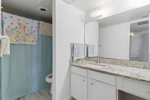 a en suite bathroom with a granite countertop sink and a mirror